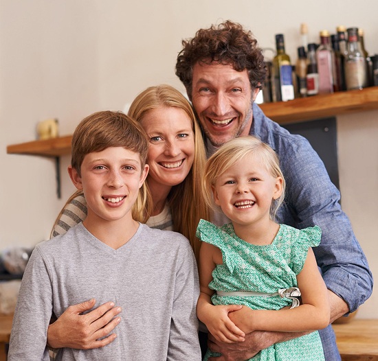 Family smiling together in a dental office, promoting a positive experience at Fairhope Children's Dentistry.